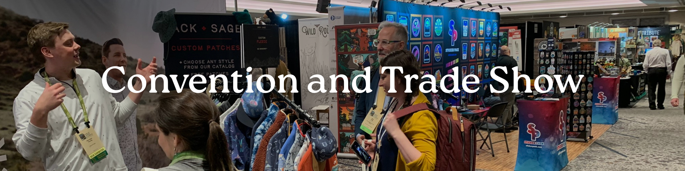 people talking in front of clothing at a trade show